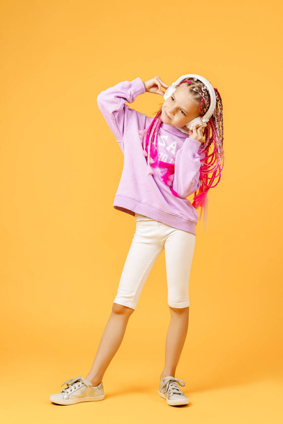 Adorable child in rounded glasses with pink dreadlocks listen to - Foto, imagen