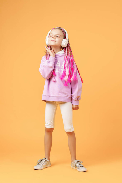 Adorable child in rounded glasses with pink dreadlocks listen to - Valokuva, kuva