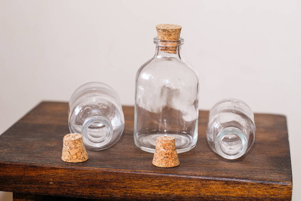 Un primer plano de las tres botellas de vidrio con corchos en la mesa de madera - Foto, Imagen