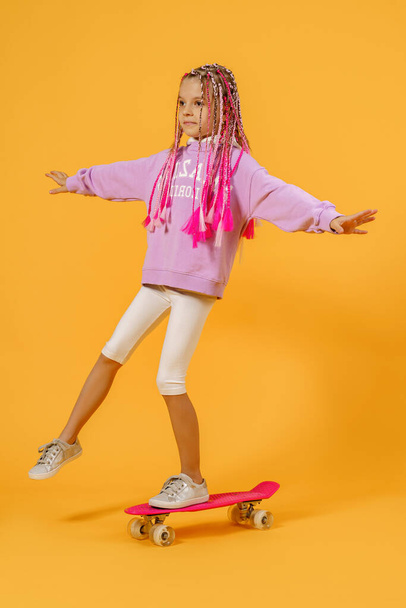 Active young girl in pink shirt and white shorts holding skatebo - Photo, Image
