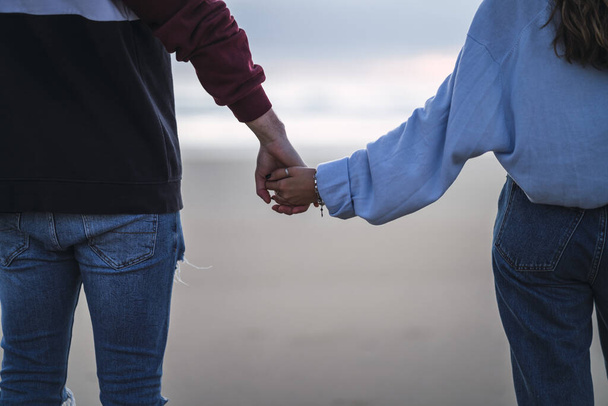 A closeup shot of a couple holding hands on the beach - Foto, imagen