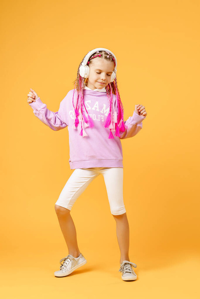 Adorable child in rounded glasses with pink dreadlocks listen to - Foto, Imagen