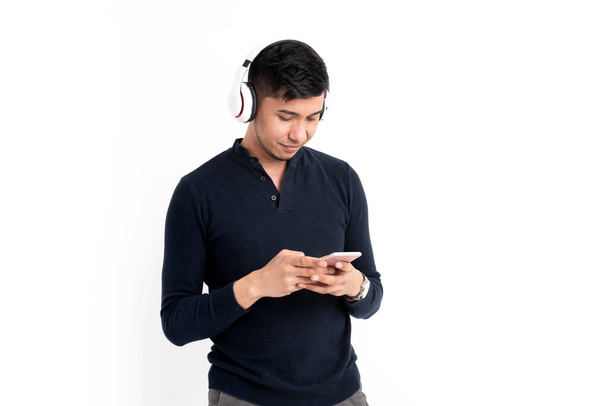 A Caucasian man with headphones and a mobile phone isolated on a white background - Fotoğraf, Görsel