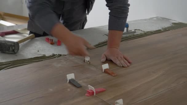 CLOSE UP: Bauunternehmer legt Keile, um verlegte Fliesen zu versiegeln und trocknen zu lassen. - Filmmaterial, Video