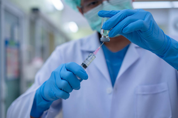 Ο γιατρός ετοιμάζει ένα εμβόλιο για να τοποθετηθεί σε στείρους ενισχυτές για χρήση σε ασθενείς που έχουν μολυνθεί από τον πανδημικό ιό.. - Φωτογραφία, εικόνα