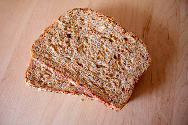 бутербродні скибочки цілої пшениці мультизерновий хліб дерев'яний кухонний стіл
 - Фото, зображення