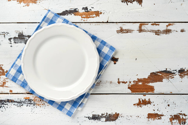 Empty white plate and blue towel over old white wooden table background for your recipe or menu. Top view. Mock up. - Valokuva, kuva