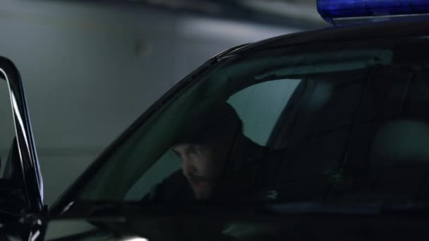 Rendőr áll a rendőrautó ajtaja mögött. Rendőrautóra céloz. - Felvétel, videó