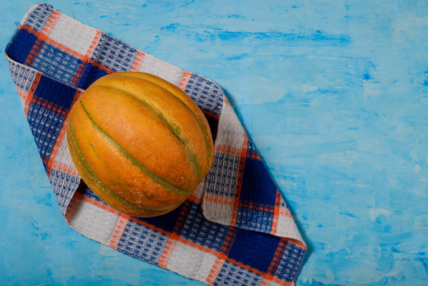 Sweet ripe yellow melon on towel, blue painted background. Organic seasonal farm fruits. Healthy vegan food. Copy space. - Photo, Image