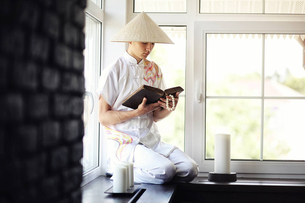 Asian boy monk in kimono reading an old book  - Фото, изображение