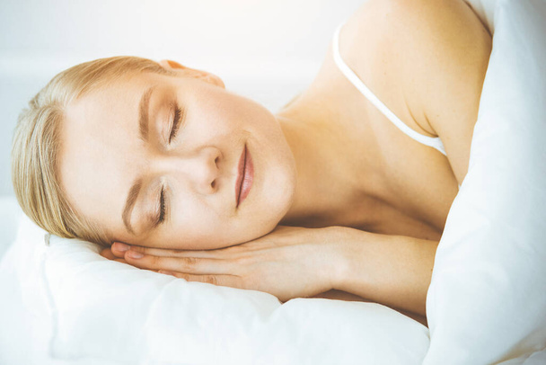 Happy woman sleeping in bedroom comfortably and blissfully. Waking up in sunny morning - Valokuva, kuva