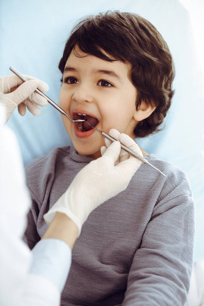 Little arab boy sitting at dental chair with open mouth during oral checking up with dentist doctor. Stomatology concept - Photo, Image