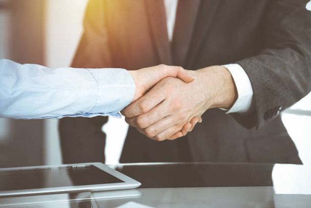 Unknown diverse business people are shaking hands finishing contract signing in sunny office, close-up. Business handshake concept - Foto, immagini