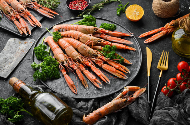 Boiled Scampi with parsley and spices on a black stone plate. Norway lobster on a black stone background. Top view. Free copy space. - Valokuva, kuva