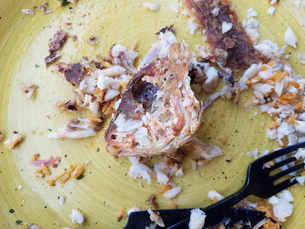 cabeza de pescado frito comido en plato amarillo con tenedor - Foto, imagen