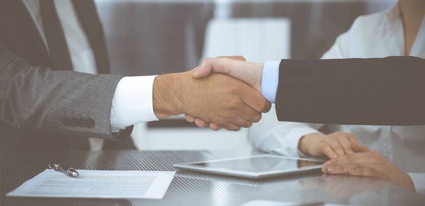 Handshake as successful negotiation ending, close-up. Unknown business people shaking hands after contract signing in modern office - 写真・画像