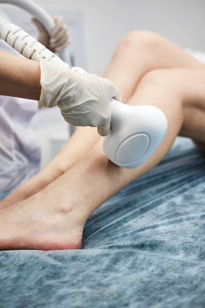the master makes the girl laser hair removal on the legs - Photo, Image