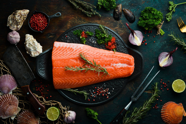 Raw salmon fillet with rosemary on a black stone plate. On a dark background. Flat lay. - Photo, image