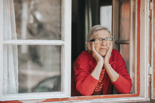 Ihastuttava vanhempi nainen tai isoäiti katselee ulos ikkunasta ja hymyilee - Valokuva, kuva