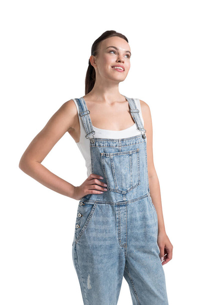 Young woman in white shirt and denim jumpsuit. Smiling student, university business education, concept of inspiration and study. Isolated over white background - Photo, image