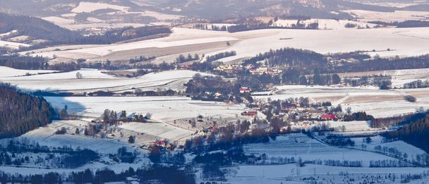 Il villaggio di Wambierzyce situato in una valle di montagna, panorama invernale da un punto di vista. C'è un punto panoramico sul sentiero escursionistico con vista sulle montagne Sowie. - Foto, immagini