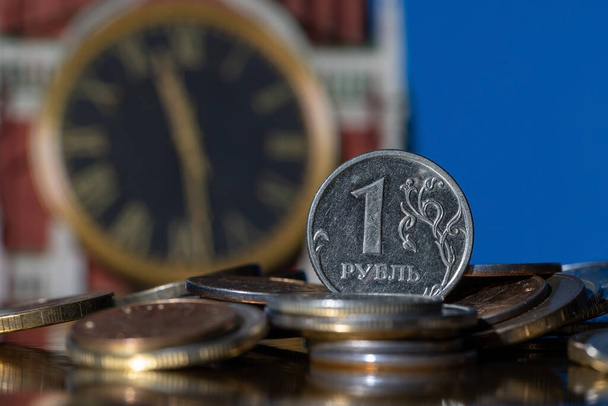 Coin in denomination of 1 Russian ruble on a pile of other coins in front of the clock on the Spasskaya Tower of the Moscow Kremlin - Fotografie, Obrázek