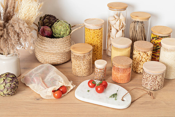 Getreide-, Getreide- und Nudelsorten in Glasgefäßen und Gemüse auf Holztisch - Foto, Bild