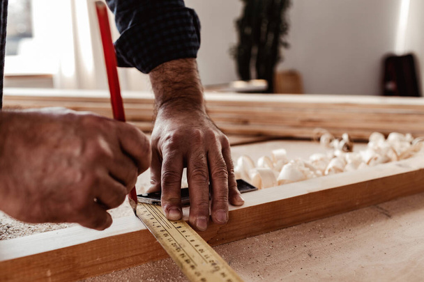 Carpenter makes pencil marks on a wood plank - Foto, Bild