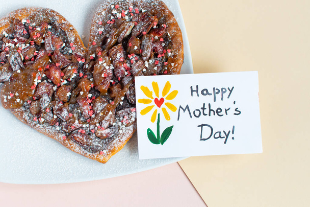 Happy mothers day sweet pizza in the shape of a heart. Breakfast Mother day. Card made by a child. Text Happy Mother day. On a pink minimal background - Foto, Imagen