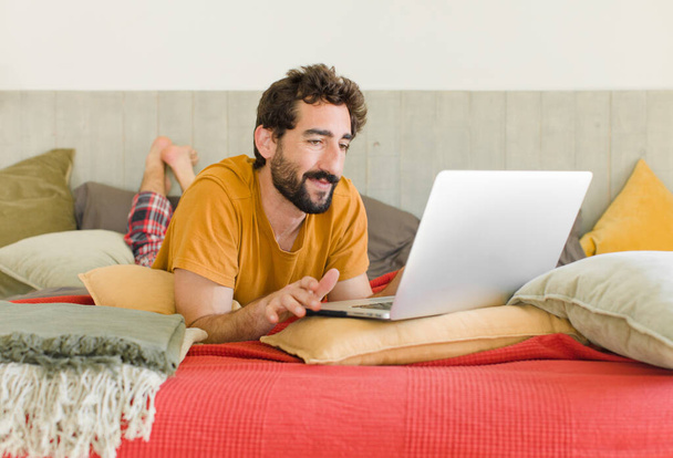 young bearded man on a bed with a laptop - Foto, afbeelding