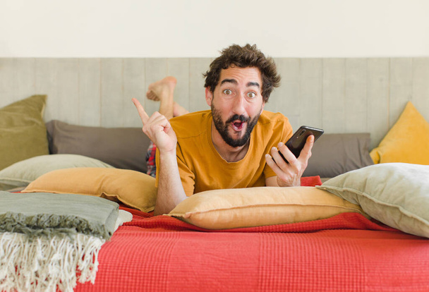 young bearded man on a bed with his mobile phone - Fotoğraf, Görsel
