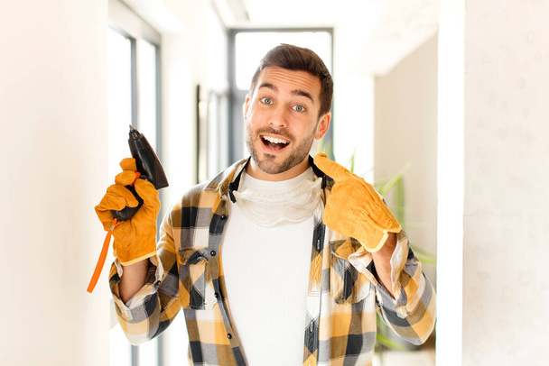 handyman smiling confidently pointing to own broad smile, positive, relaxed, satisfied attitude - Foto, afbeelding