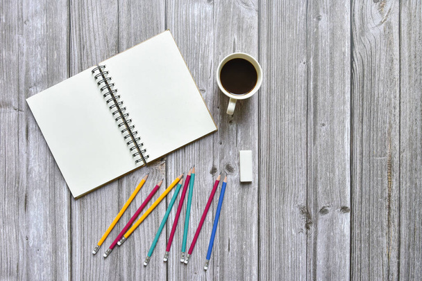 Still life, business office supplies education concept, Top view image of open notebook with coffee and various colorful pencil with blank pages on old brown wooden background, ready for adding text - Photo, Image