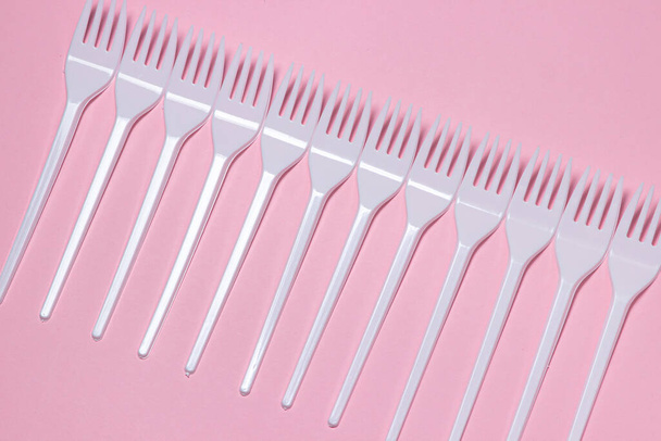 Plastic forks on a pink background. Disposable tableware. Plastic products. - Photo, image
