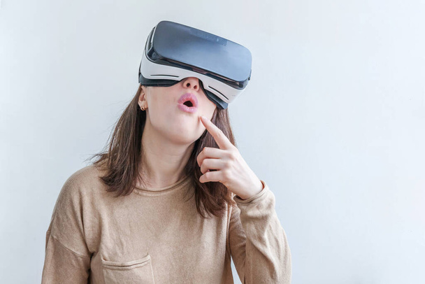 Sonríe mujer joven usando realidad virtual gafas VR casco auriculares sobre fondo blanco. Smartphone con gafas de realidad virtual. Tecnología, simulación, alta tecnología, concepto de videojuego - Foto, imagen