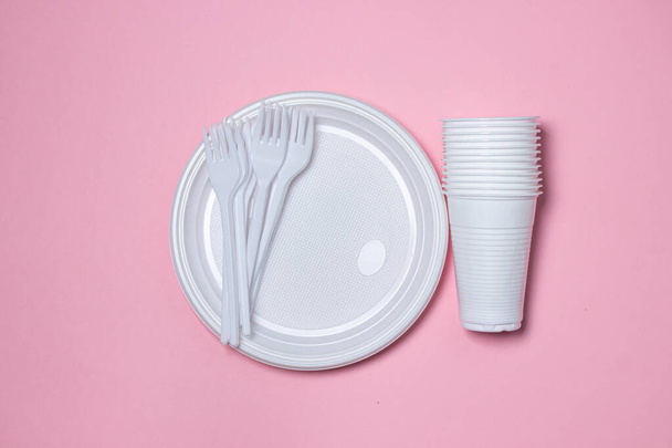 Plastic dishes on a pink background. Disposable tableware. Plastic products. - Фото, зображення