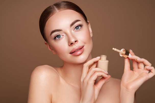 Πορτρέτο όμορφη νεαρή γυναίκα με καθαρό φρέσκο δέρμα. Μοντέλο με βάση μπουκάλι μακιγιάζ. Καλλυντικά, ομορφιά και spa - Φωτογραφία, εικόνα