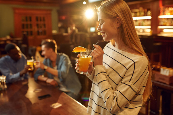 Troje przyjaciół z napojami alkoholowymi bawiących się przy stole w barze. Grupa ludzi zrelaksować się w pubie, nocny styl życia, przyjaźń, uroczystości imprezy - Zdjęcie, obraz