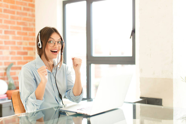 pretty telemarketer feeling shocked, excited and happy, laughing and celebrating success, saying wow! - Foto, imagen