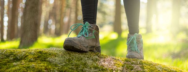 person walking through the forest in nature. Healthy life style. Boots in the foreground - Photo, Image