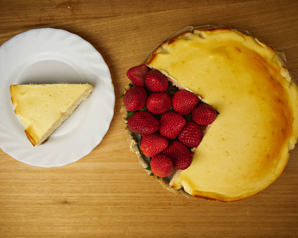 Gâteau au fromage avec plusieurs fraises sur fond bois. Vue du dessus - Photo, image