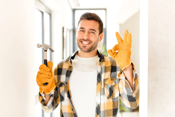 handyman feeling happy, relaxed and satisfied, showing approval with okay gesture, smiling - Фото, зображення