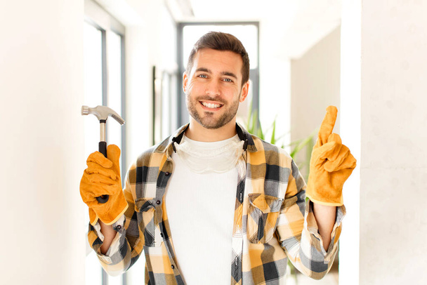 handyman smiling and looking friendly, showing number one or first with hand forward, counting down - Foto, afbeelding