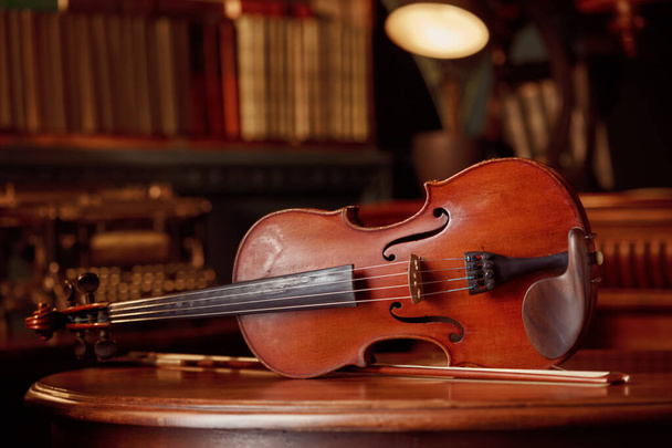 Geige im Retro-Stil auf Holztisch, Nahaufnahme, niemand. Klassisches Saiteninstrument, Musikkunst, alte Viola, dunkler Hintergrund - Foto, Bild