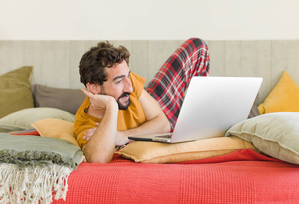 young bearded man on a bed with a laptop - Foto, imagen