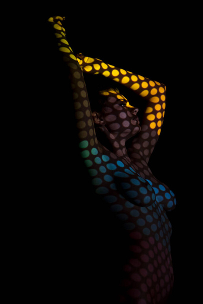 Nude girl with a projection on the body on a black background - Photo, image