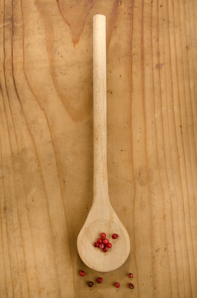 roze peper op een houten lepel - Foto, afbeelding