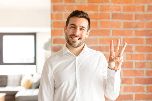 handsome businessman smiling and looking friendly, showing number three or third with hand forward, counting down - Photo, Image