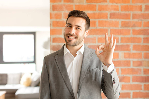 handsome businessman feeling happy, relaxed and satisfied, showing approval with okay gesture, smiling - Photo, image