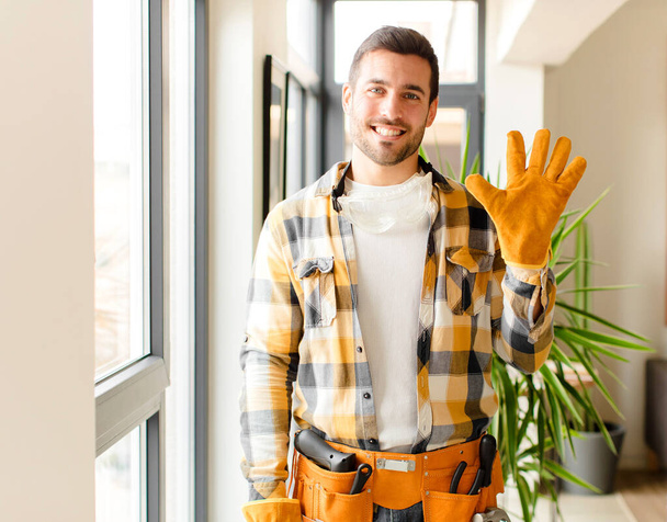 handyman smiling and looking friendly, showing number five or fifth with hand forward, counting down - Photo, image